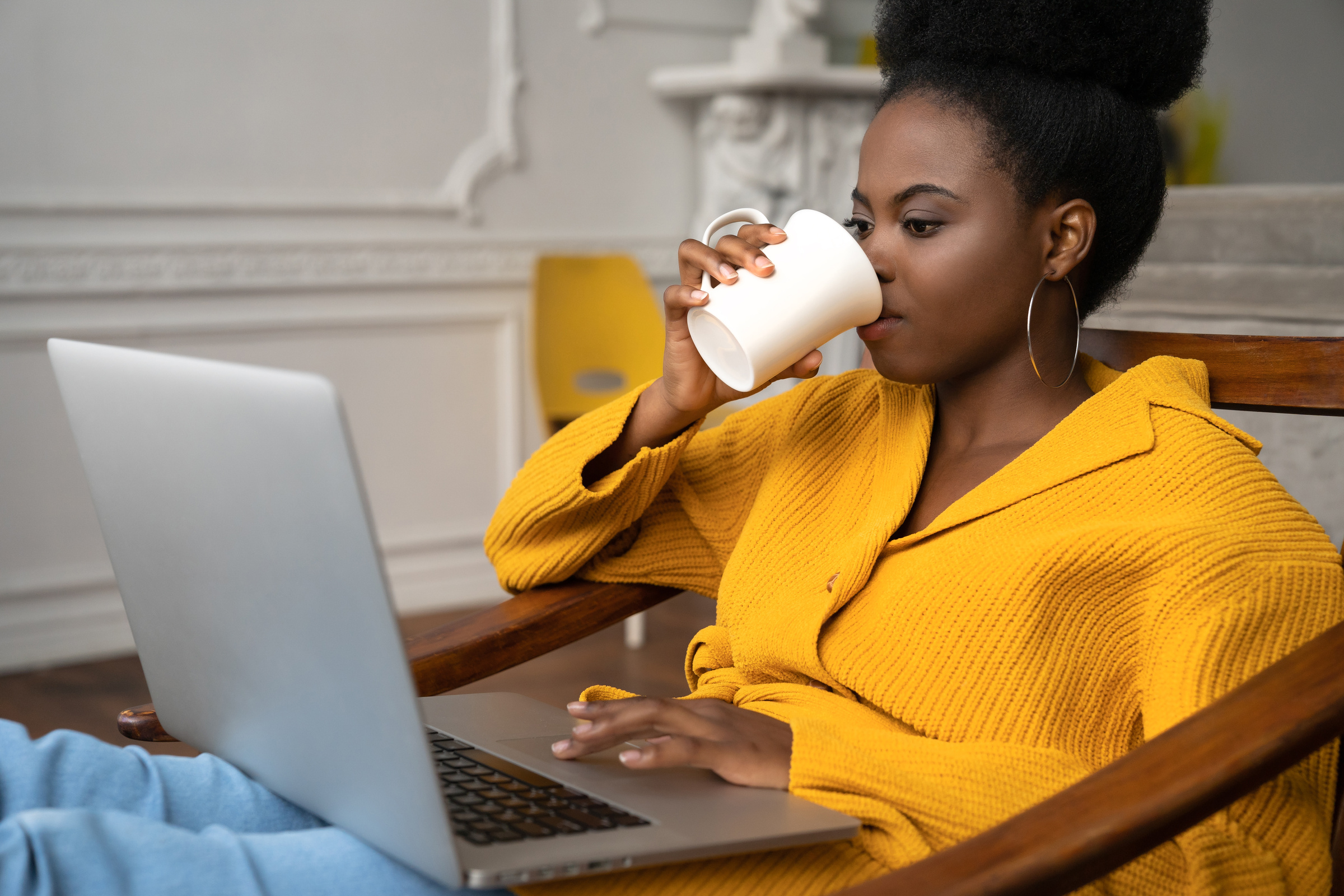Woman Drinking Coffee While Using a Laptop